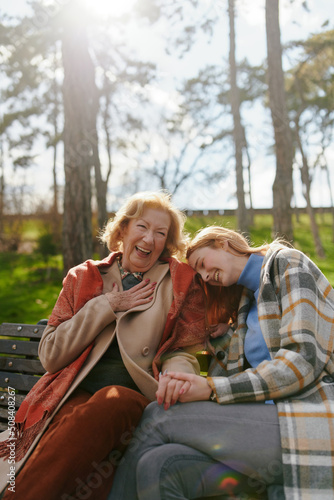 Foto A grandmother is laughing and having fun with her adolescent granddaughter while sitting on the park bench
