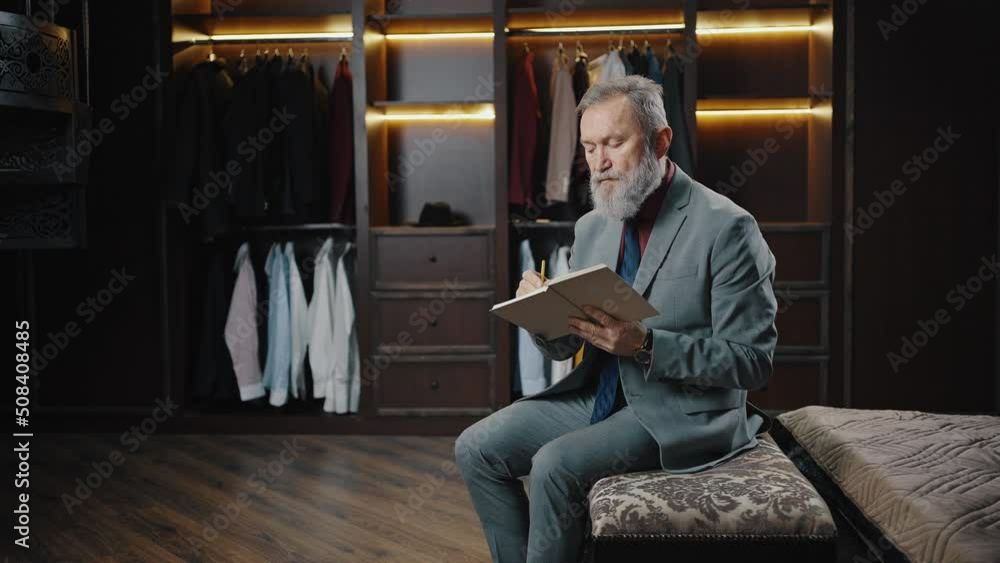 Successful pensive mature bearded businessman planning his day, writing list in notebook at dressing room, empty space Successful pensive mature bearded businessman planning his day, writing list in notebook at dressing room, empty space