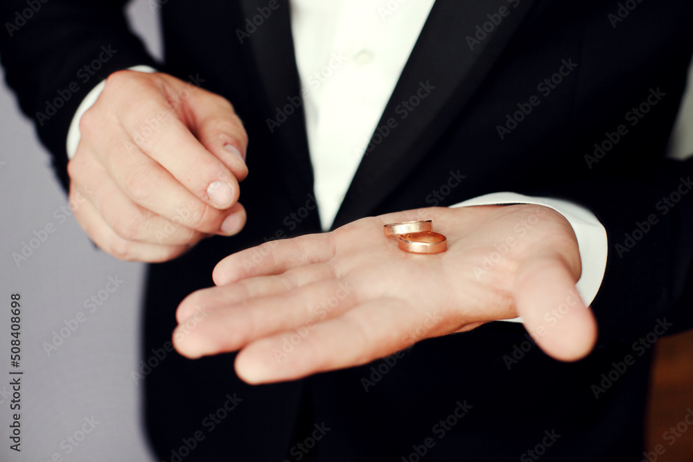 Fototapeta premium Preparing for wedding. Groom buttoning cufflinks on white shirt before wedding. Groom's clothes. Close up.