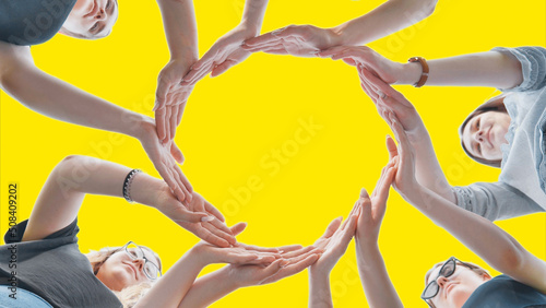 Friends make a circle with their palms on a yellow background.