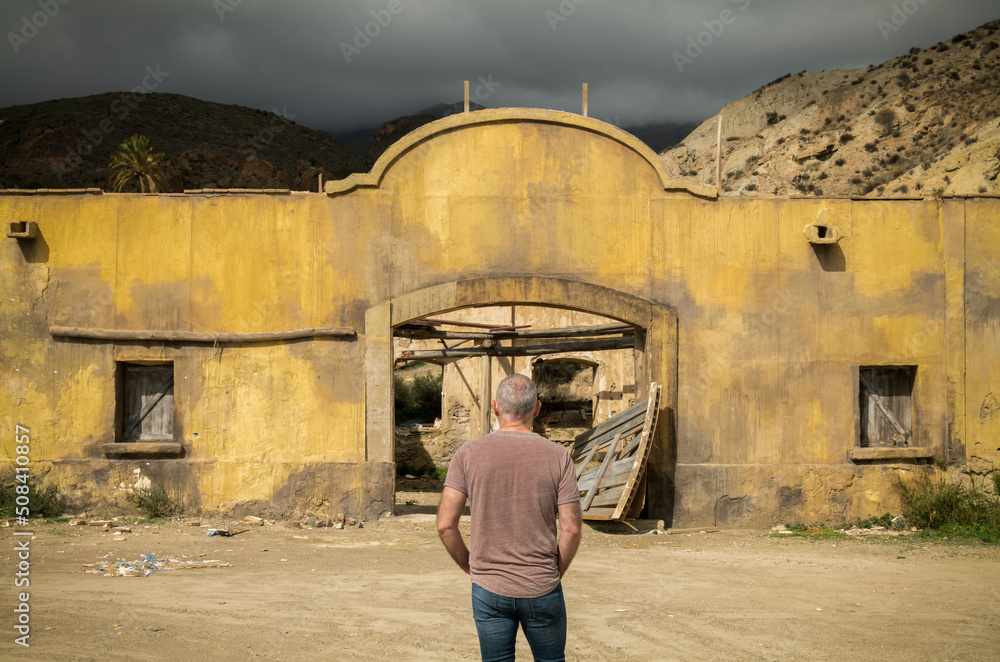 Rear view of adult man standing in front of an abandoned building