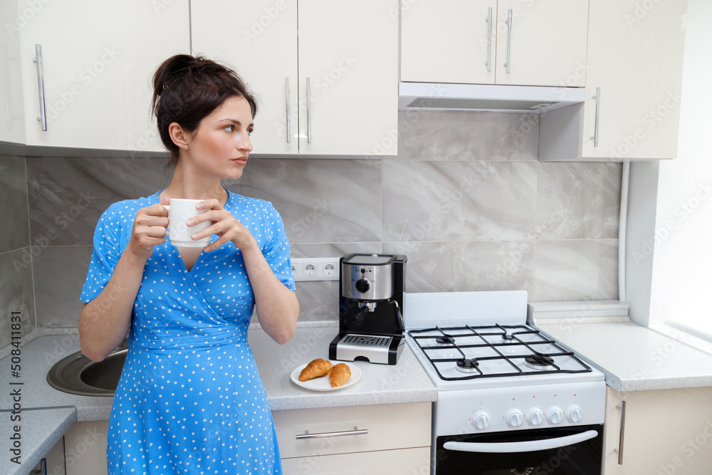 woman in the morning in the kitchen with coffee near the coffee machine woman in the morning in the kitchen with coffee near the coffee machine