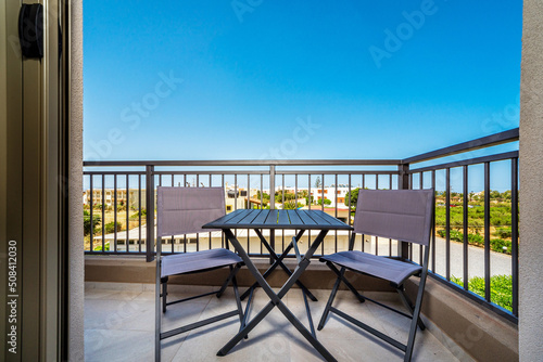 View to the balcony. There are  two modern chairs and table, garden furniture. © Maksym