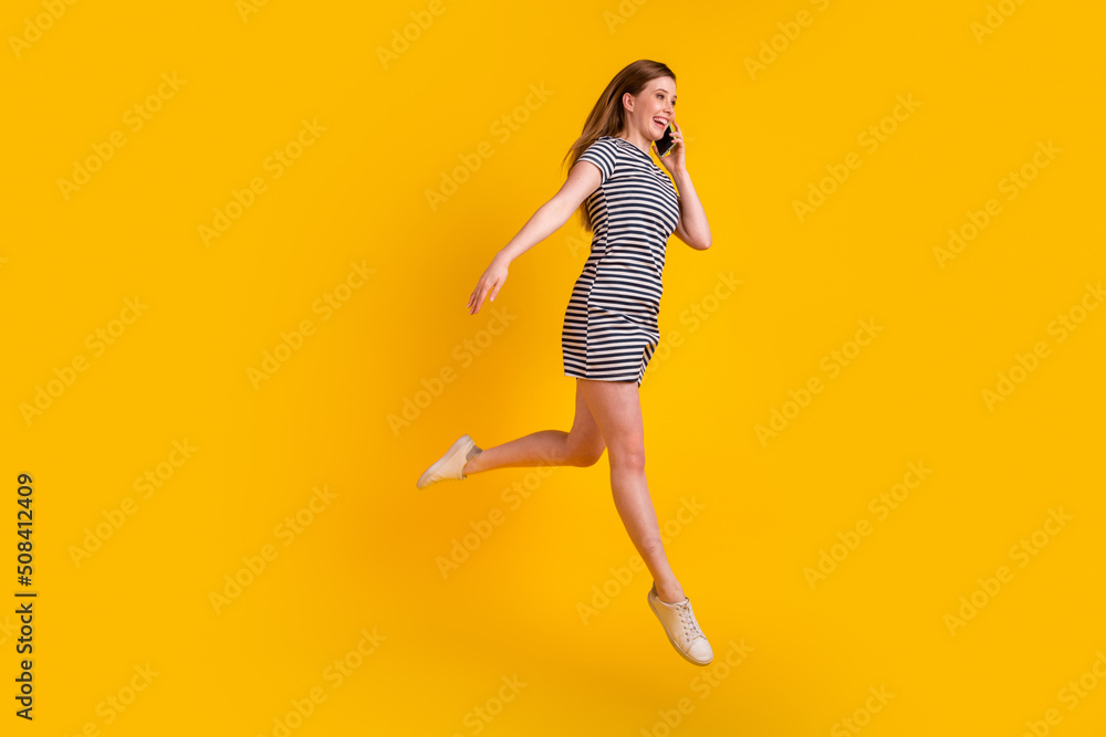 Full size profile side photo of young girl jump up talk communication mobile isolated over yellow color background Full size profile side photo of young girl jump up talk communication mobile isolated over yellow color background