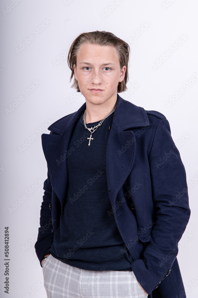 Porträt junger Mann mit langen Haaren mit blauem Pullover und Mantel ernst blickend