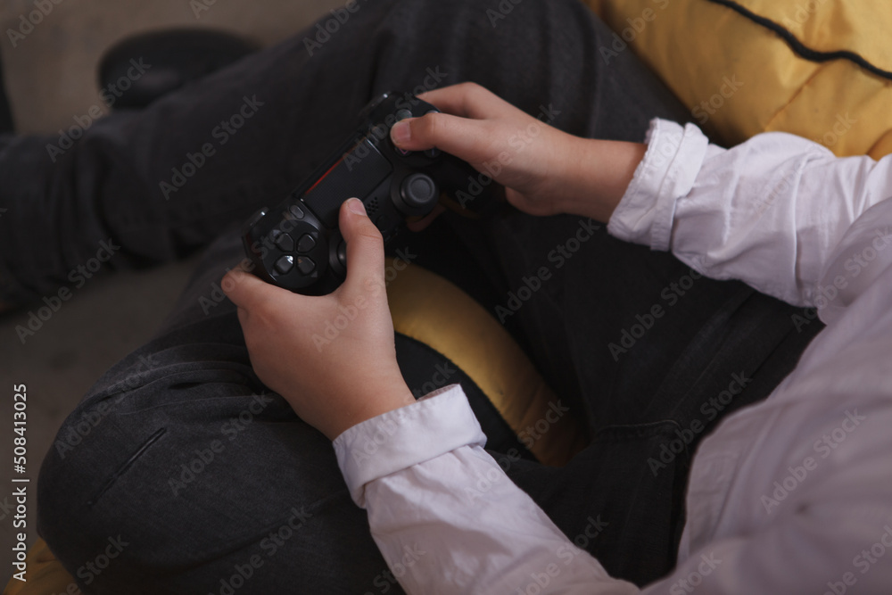 Cropped top view close up of a child holding console joystick, playing video games