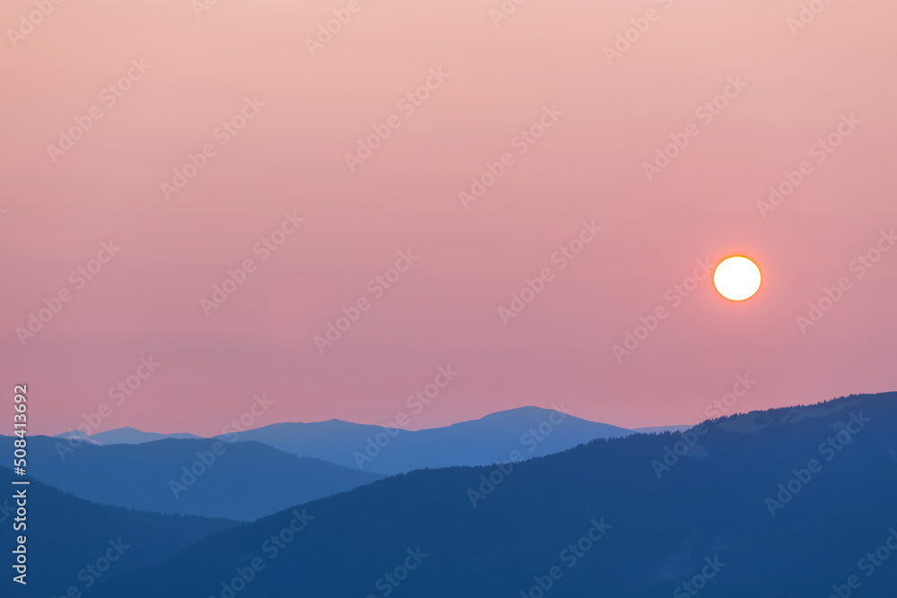 mountain chain silhouette in blue mist at the pale sunrise, natural mountain travel background