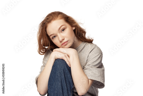 Pretty redhead young girl with long curly hair looking at camera with light smile isolated on white background. Concept of youth, beauty, lifestyle