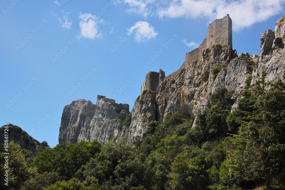 Mountain forest with the ruins of the medieval Peyrepertuse Castle on steep rocks in Duilhac, Occitanie region in France