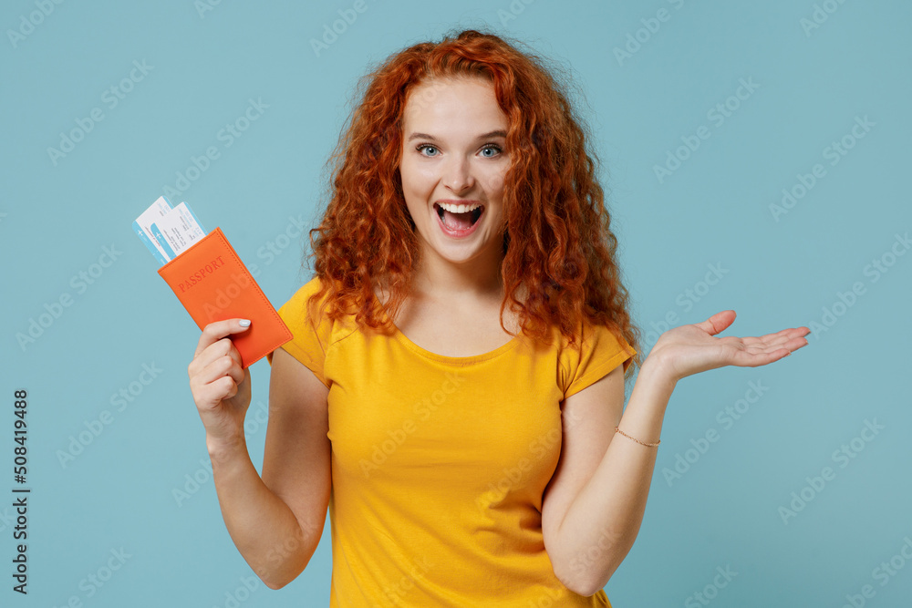 Traveler tourist woman in yellow t-shirt hold passport boarding tickets isolated on plain pastel light blue background studio. Passenger travel abroad on weekends getaway. Air flight journey concept Traveler tourist woman in yellow t-shirt hold passport boarding tickets isolated on plain pastel light blue background studio. Passenger travel abroad on weekends getaway. Air flight journey concept