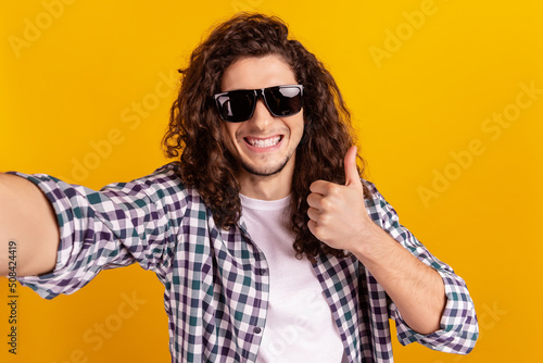Photo of young excited man show thumb-up great perfect choice recommend take selfie isolated over yellow color background
