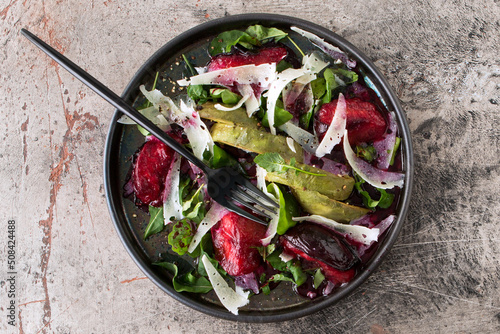 plate with salad with arugula, plums, avocado and cheese on the table