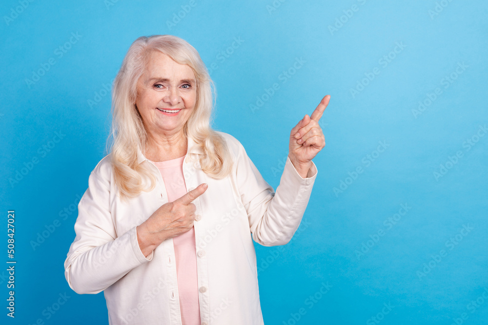 Photo of mature lady indicate fingers empty space ads recommend proposition discount isolated over blue color background Photo of mature lady indicate fingers empty space ads recommend proposition discount isolated over blue color background