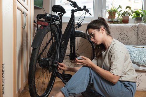 Young self learned woman or girl mechanic fixing and repairing her bicycle at her home. Female repair chain on rear wheel before she start to ride a bike on nice sunny weather.