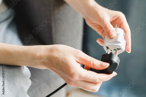 Woman applies universal travel adapter electrical plug converter power socket