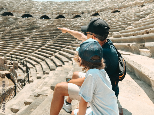 Fotografiet Young father dad and his school boy kid son tourists visiting ancient antique coliseum amphitheater ruins in hot summer day