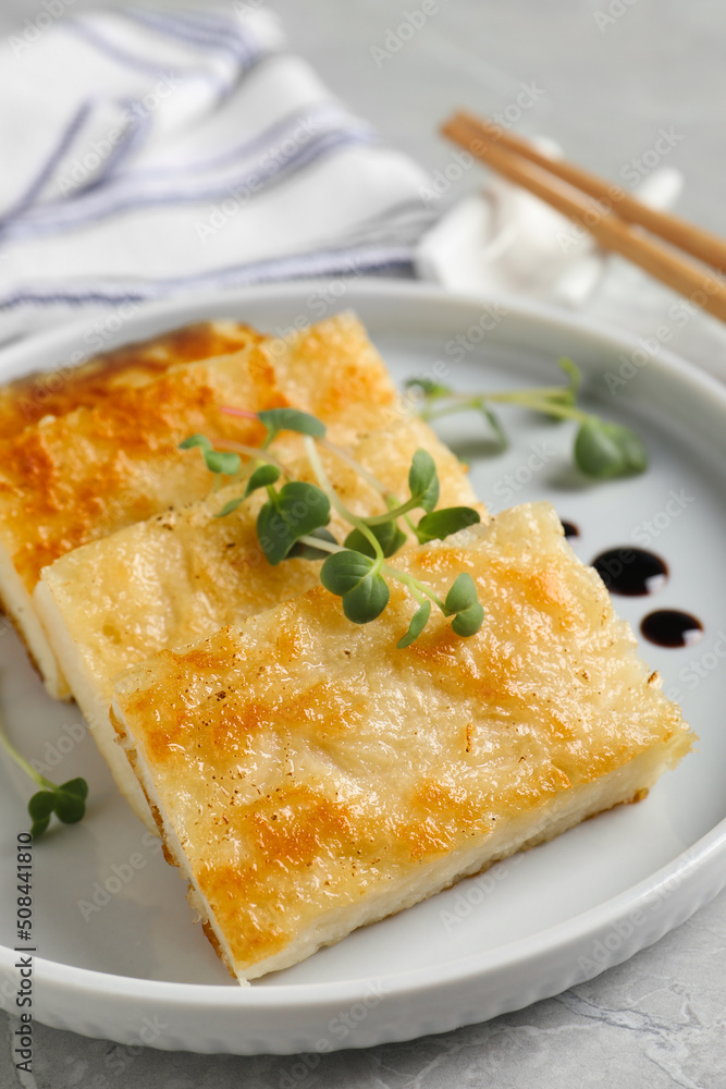 Delicious turnip cake with microgreens served on grey table, closeup Delicious turnip cake with microgreens served on grey table, closeup