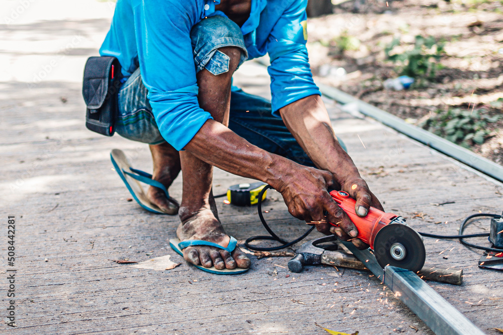 Obraz premium Cutting iron with steel cutter machine by Asian mechanic man at the construction site.