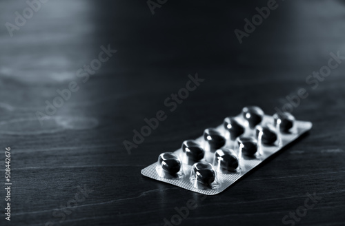 Black pills are on the table. Copy space. Close-up. Blister with medicine. Treatment tablets. Pharmacology concept. Dietary supplements. Daily health help. Banner. Medical industry. Empty text place