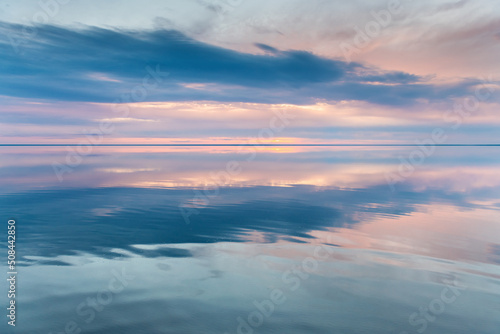 Beautiful landscape of salt lake at sunset. Blue sky with clouds are reflected in the mirror water surface. Elton lake  Russia