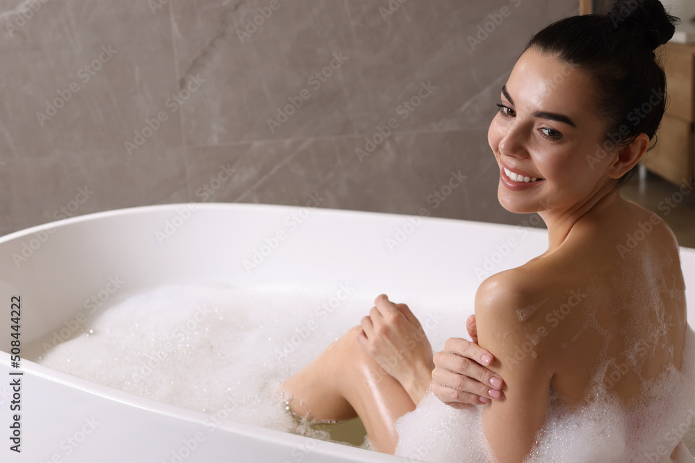 Naklejka premium Woman taking bath with shower gel indoors