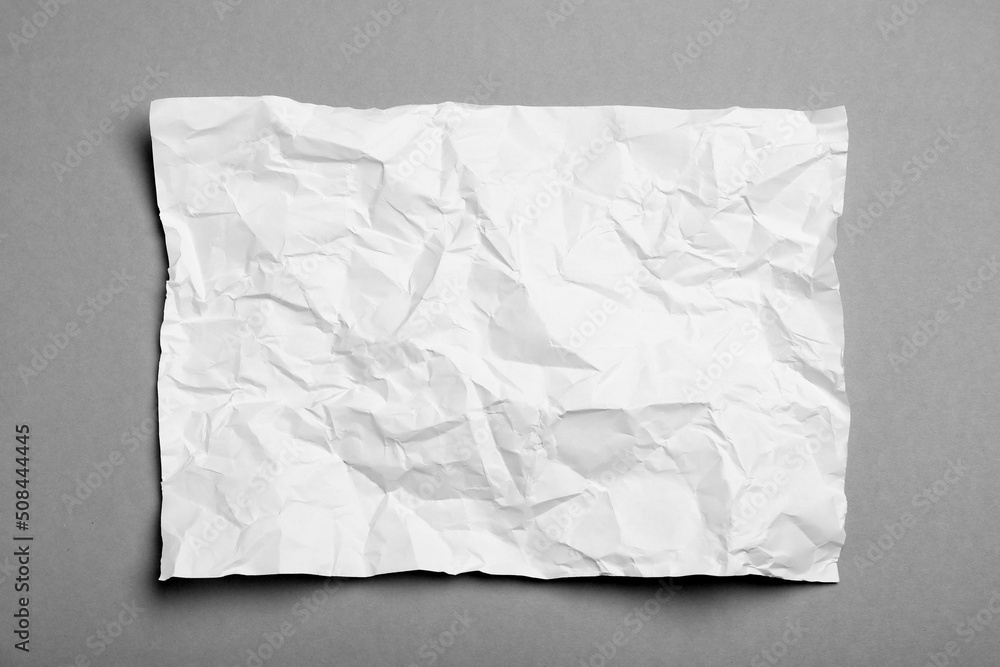 Sheet of white crumpled paper on grey background, top view Sheet of white crumpled paper on grey background, top view