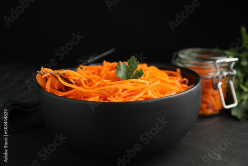 Delicious Korean carrot salad with parsley in bowl on black table