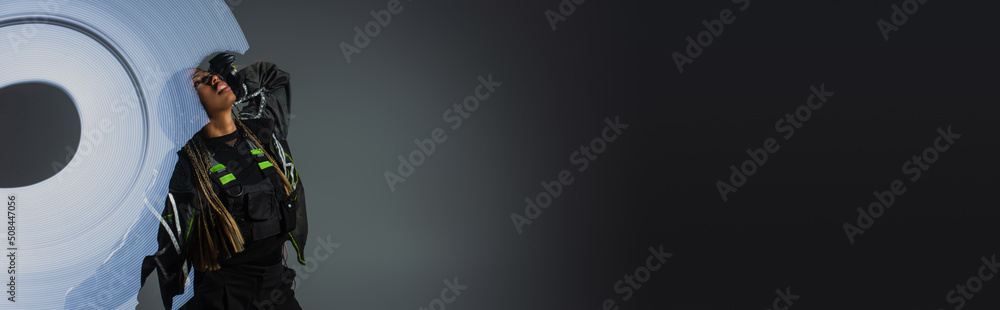 Sequence shot of stylish african american woman posing near abstraction on grey background, banner.