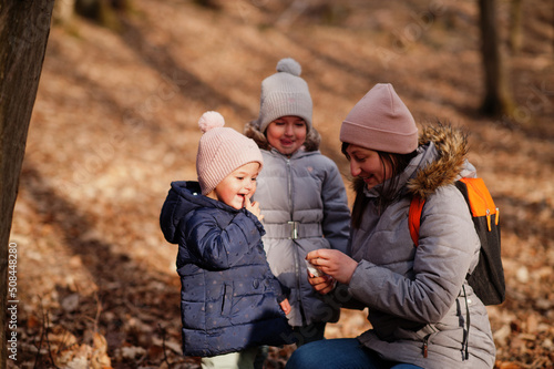 Mother with daughters wear jacket and hat in early spring forest. © AS Photo Family