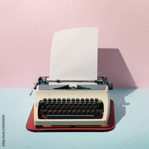 Pastel pink and blue background against retro vintage typing machine and paper. Creative retro concept. Retro futurism.