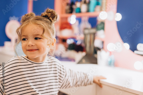 Portrait of a little beautiful girl with a stylish hairstyle in a beauty salon, expressing happiness of the pretty kid © Ananass