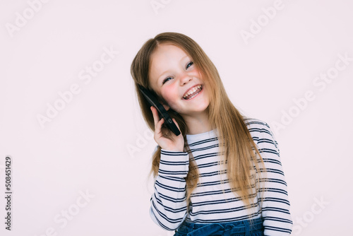 The little girl phones on white wall background