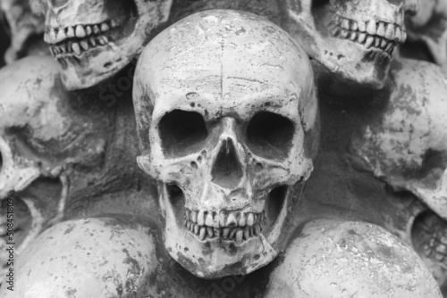 Close-up black and white photo of skulls against background of other skulls as reminder of death in form of skull or fear of death with skull