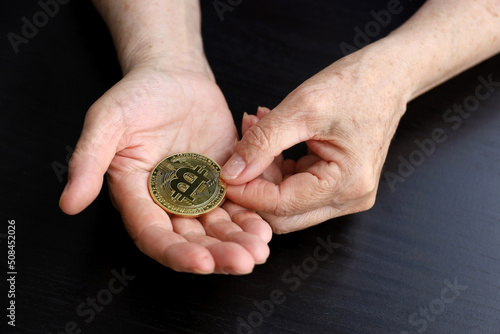 Bitcoin in wrinkled hands of elderly woman  concept of retirement savings. Electronic decentralized money  crypto currency
