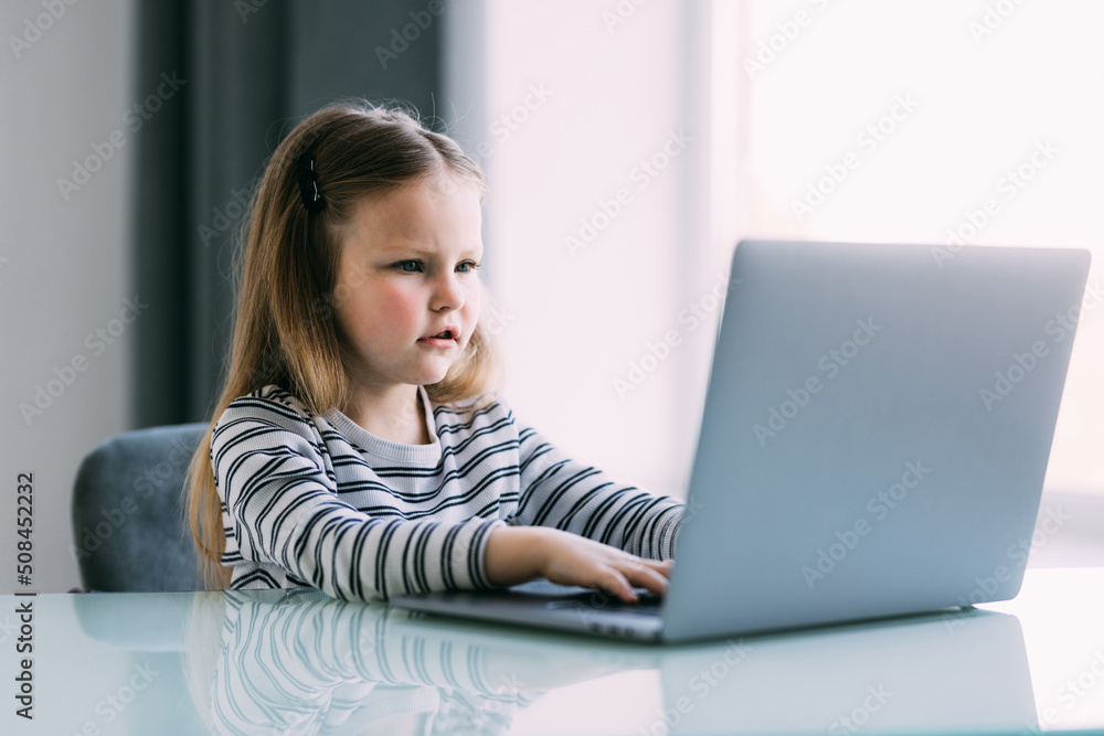 Little girl learning English indoors at online lesson on laptop Little girl learning English indoors at online lesson on laptop