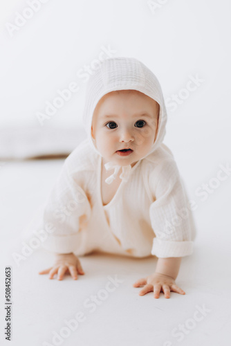 Cute studio portrait of a little newborn which has already begun to crawl. The child laughs and rejoices in his first little steps