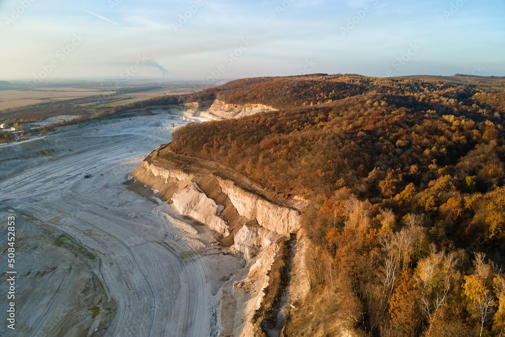 Aerial view of open pit mining site of limestone materials for construction industry with excavators and dump trucks