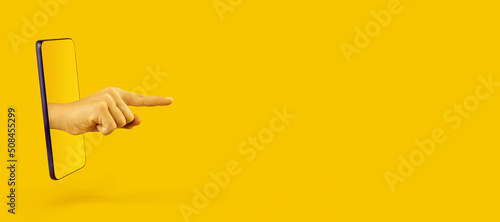 Hand pointing to something by forefinger from smartphone on yellow background. Gesture of choice. Online technology and communications concept.