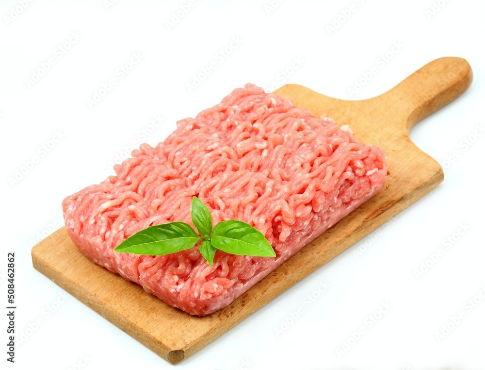 Raw minced pork on the chopping board. Pork meat on the white background, decorated with basil leaf