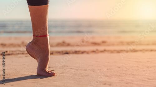 foot on tiptoe in balance on sand of beach with sun rays photo