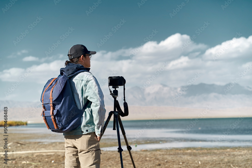 asian photographer looking at view by a lake