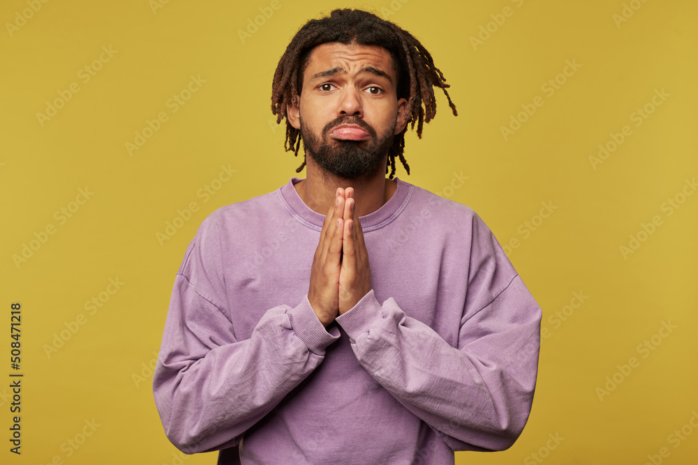 Studio portrait of young african american man posing over studio background curving his lip and please somebody Studio portrait of young african american man posing over studio background curving his lip and please somebody