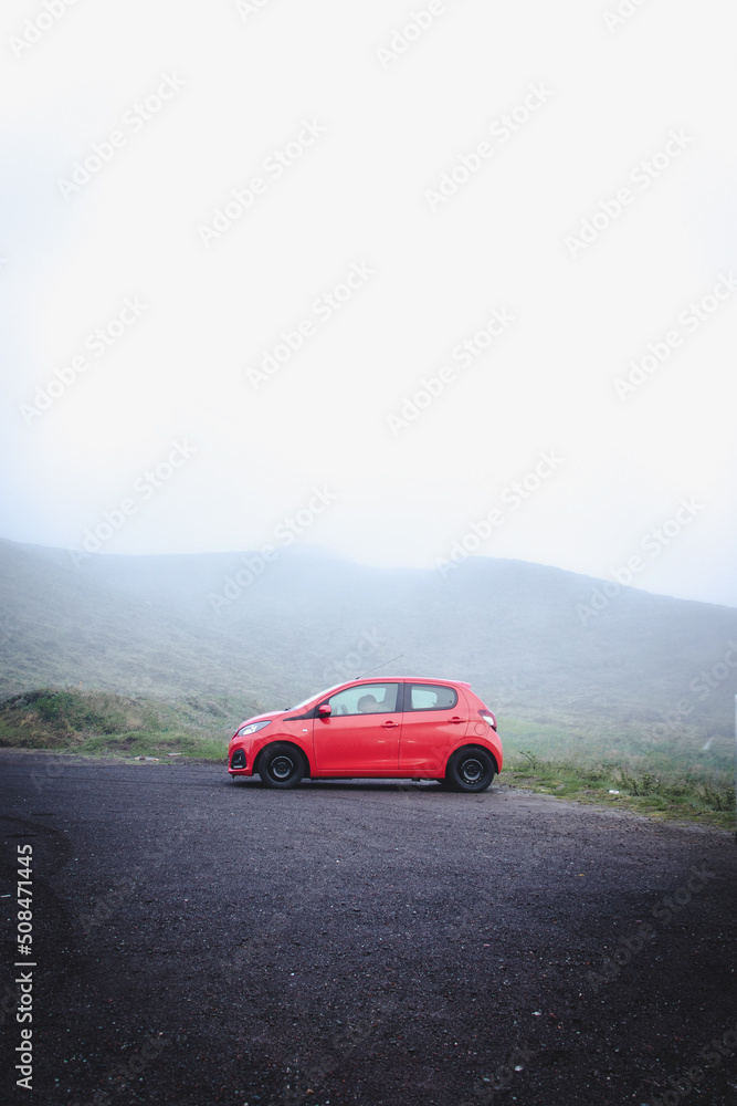 Fototapeta premium Red car in nature with fog, Azores