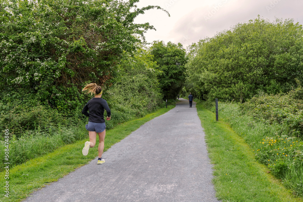 Female running in a park, Sport and fitness concept. Woman jogging on a small pathway. Female running in a park, Sport and fitness concept. Woman jogging on a small pathway.