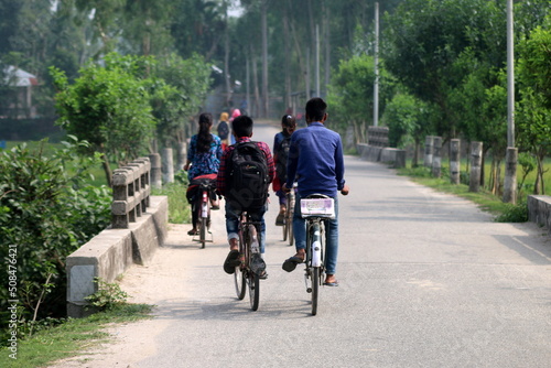 Village Students with backpack are going to school for their study or Education on Bycle.that is very common scenery at Bangladesh. Portrait photo.