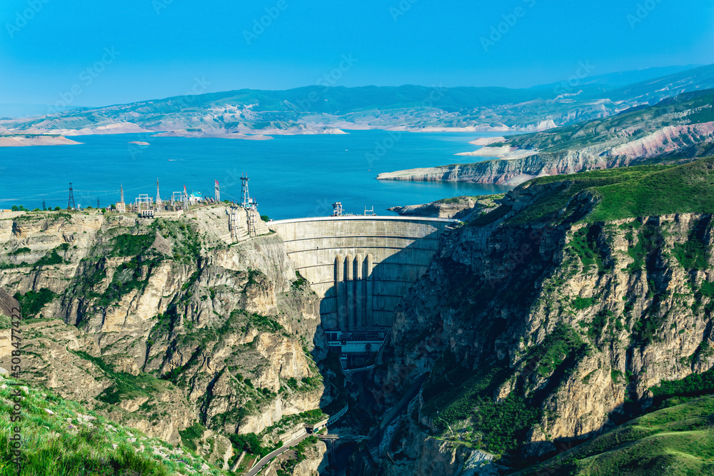 mountain landscape with an arched hydroelectric dam and a reservoir in the canyon