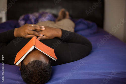 Reading in bed and American American or black man looking at orange literature book © rohane