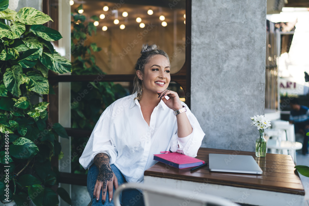 Cheerful Caucasian woman in white shirt smiling during time for doing distance job in terrace coworking space, happy female copywriter with textbook and closed laptop enjoying freelance lifestyle Cheerful Caucasian woman in white shirt smiling during time for doing distance job in terrace coworking space, happy female copywriter with textbook and closed laptop enjoying freelance lifestyle
