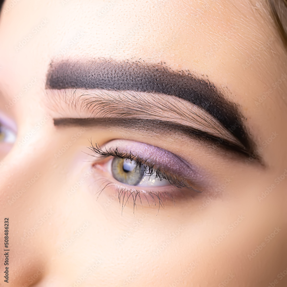 close-up of the model's eyebrow on which black paste is applied to build the shape of the eyebrows