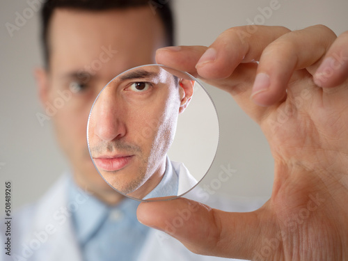 Eye care professional optometrist doctor man holding a glass lens inside laboratory photo